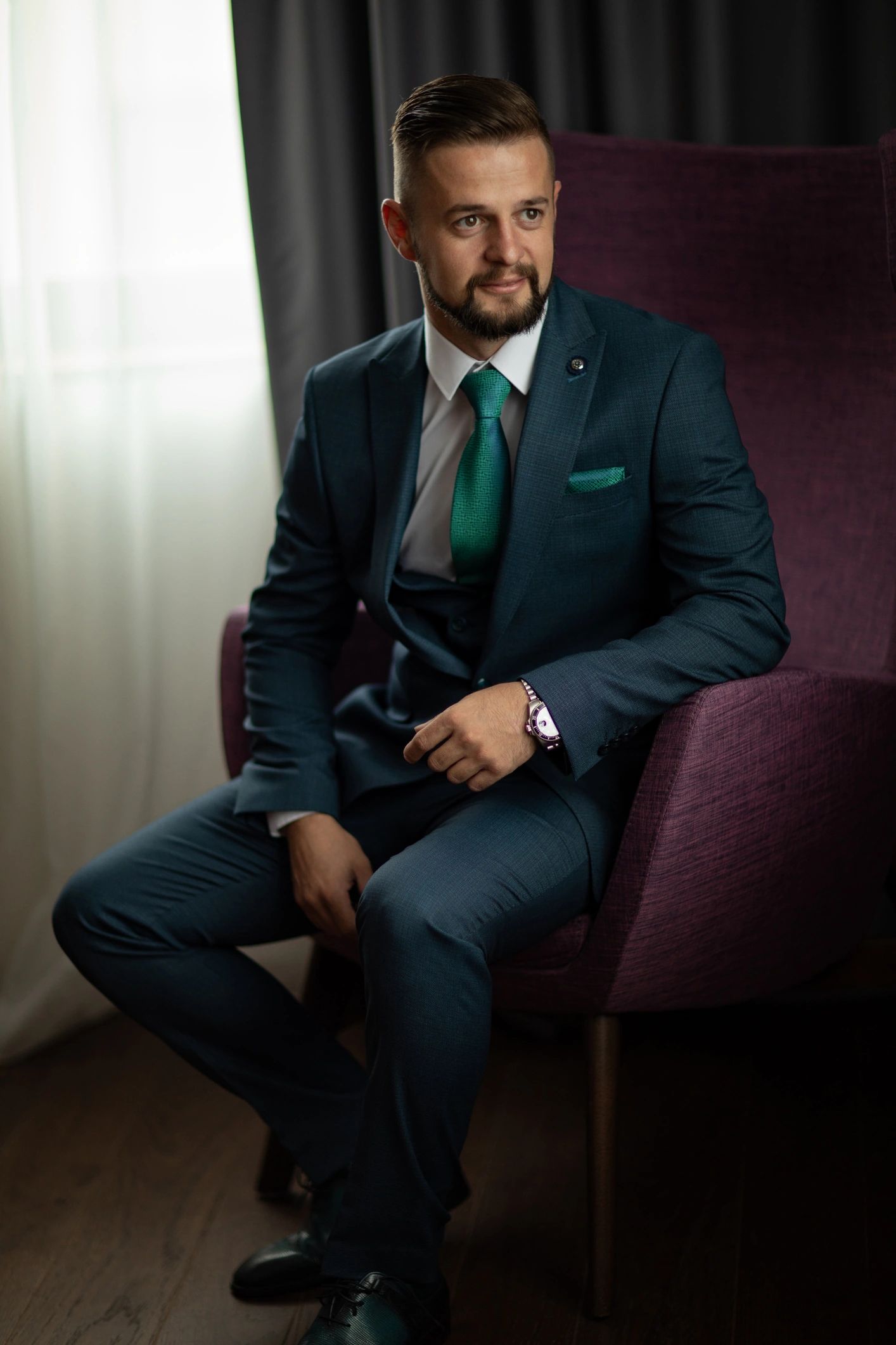 Man wearing a tailored suit seated in a chair